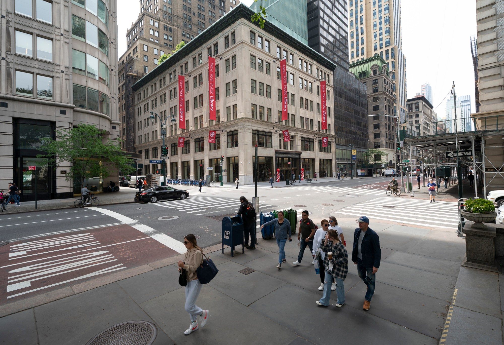 People pass a library at a busy Manhattan intersection